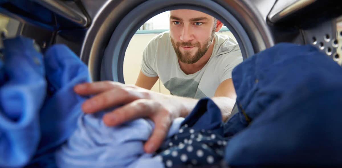 Photo d'un homme sortant le linge de sa machine à laver