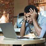 jeune homme étudiant stressant devant son ordinateur portable à cause de sa formation a distance