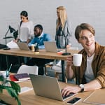 jeune personne web developper en freelance dans un open space avec d'autres personnes en arrière plan