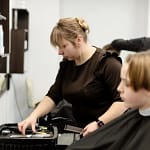 femme en train de chercher ses outils de coiffure pour coiffer une cliente apres s'être reconvertie au métier de coiffeuse
