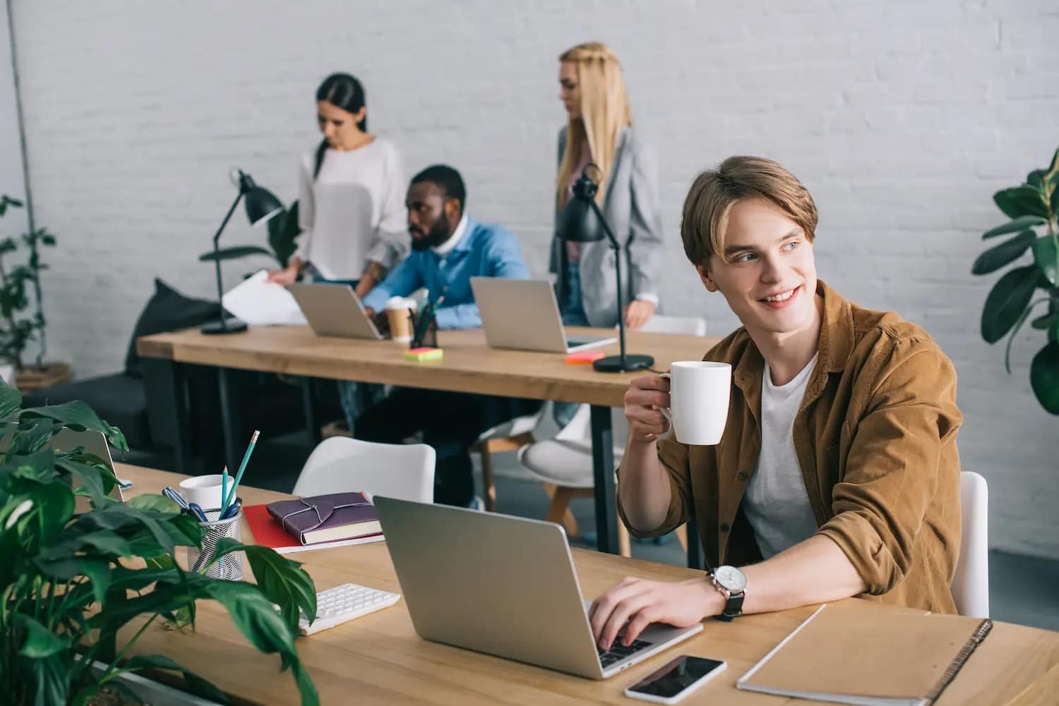 jeune personne web developper en freelance dans un open space avec d'autres personnes en arrière plan