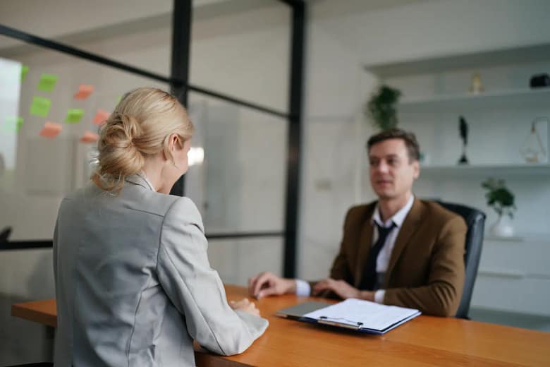entretien d'embauche entre une femme blonde et un homme d'âge moyen dans un bureau d'entreprise